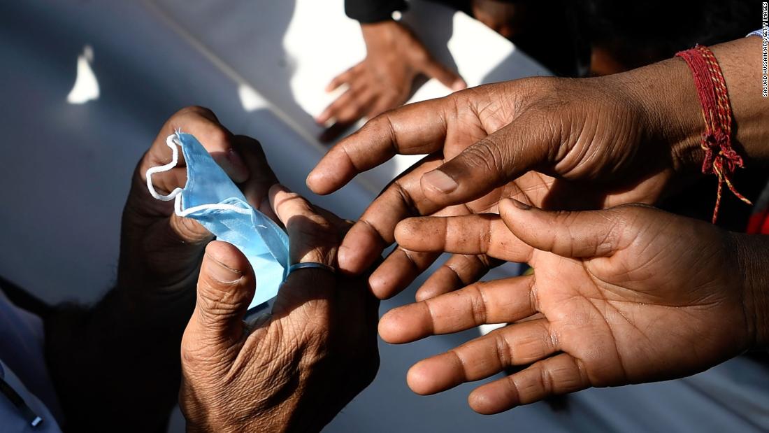 People gather to collect free face masks in New Delhi on March 17.